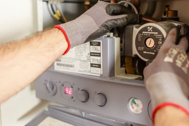 Technicien agréé réglant une chaudière au gaz lors de l'entretien